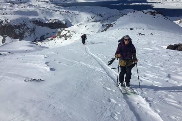 Una mujer rando está esquiando por una montaña cubierta de nieve.