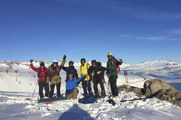 Un grupo de randos parados en la cima de una montaña cubierta de nieve.