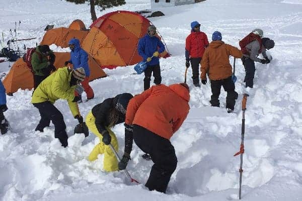 Un grupo de rando trabajando en la nieve cerca de tiendas de campaña.