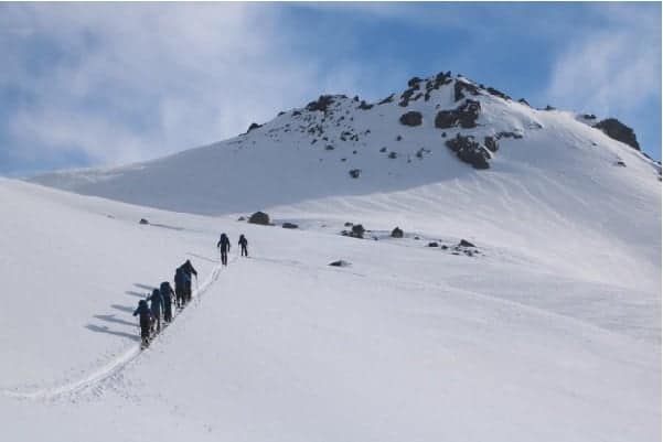 Un grupo de randos subiendo una montaña cubierta de nieve.