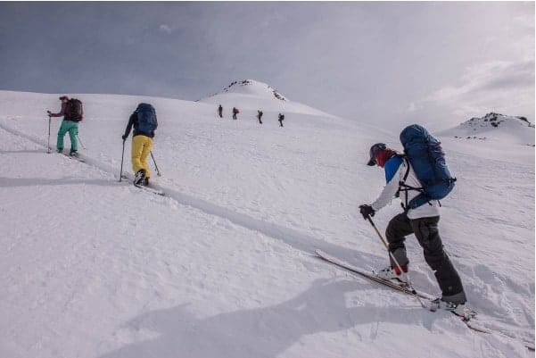 Un grupo de gente rando esquiando por una montaña nevada.