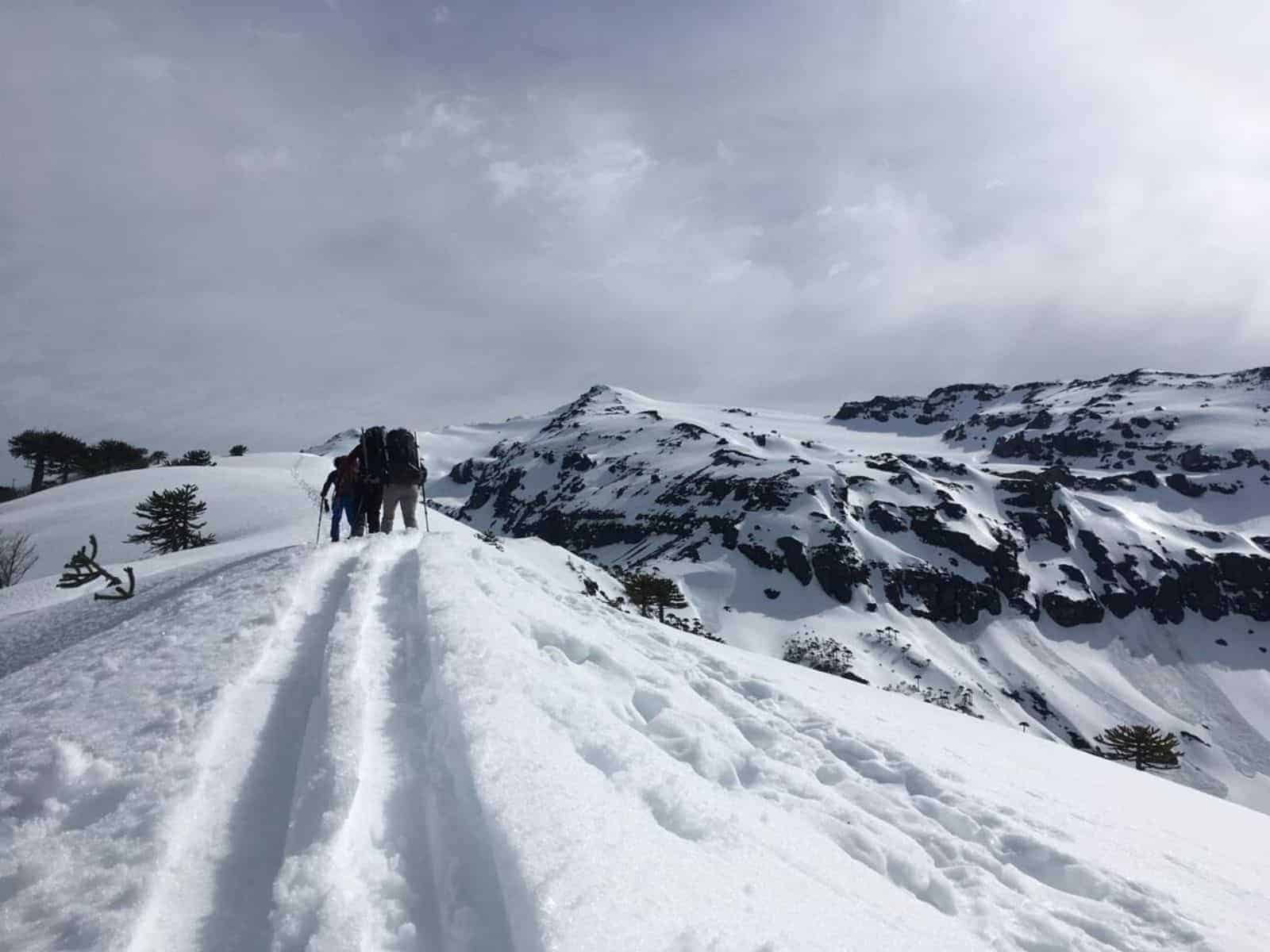 Un grupo de personas subiendo una montaña cubierta de nieve cerca de un volcán.