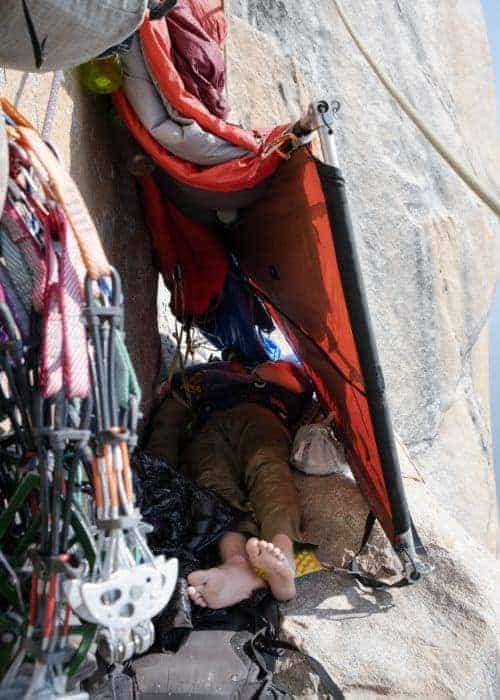 Una persona durmiendo en una tienda salathé encima de una roca.