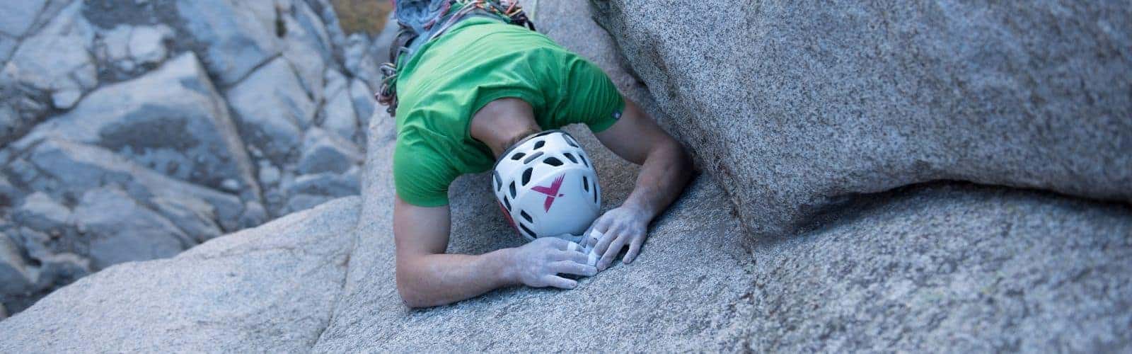 Una persona tirada con cinta adhesiva sobre una roca con un casco puesto.