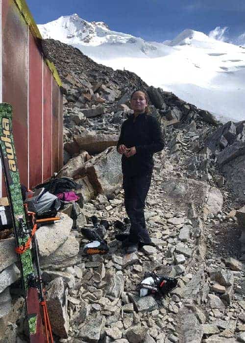 Un hombre parado frente a una montaña con esquís a gran altura.