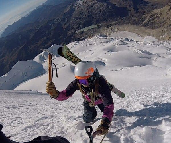 Una persona asciende a mayores altitudes mientras esquía en una montaña nevada.