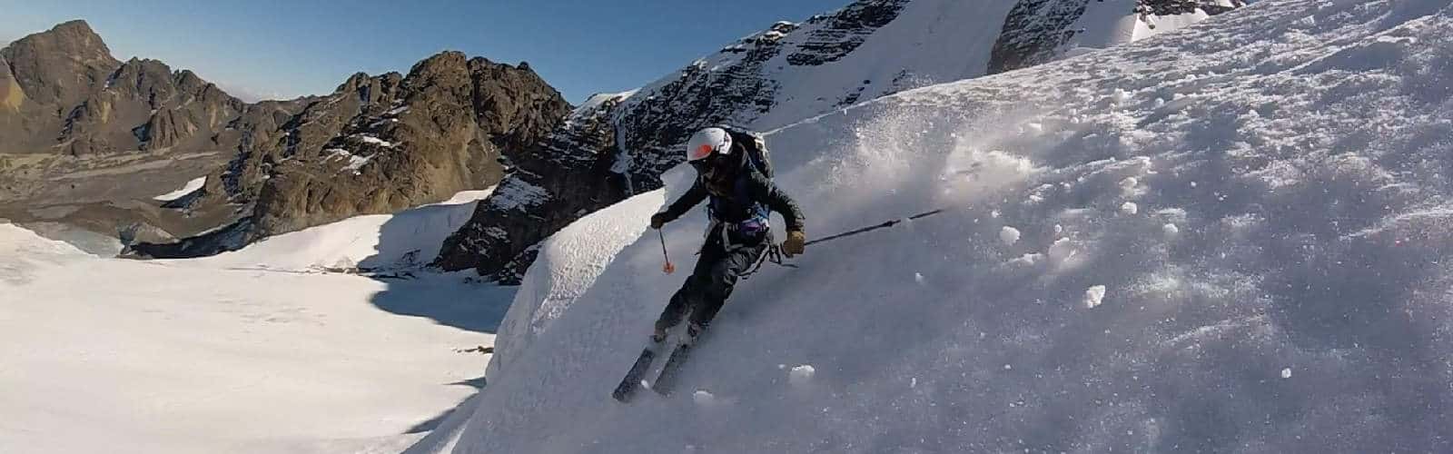 Un esquiador desciende una montaña nevada a gran altura.