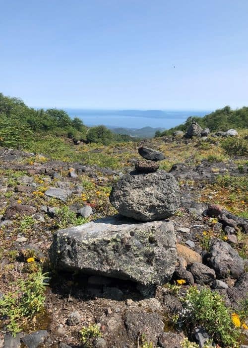 Una pila de rocas en la cima de una colina con vista al océano cerca del Volcán Rukapillan.