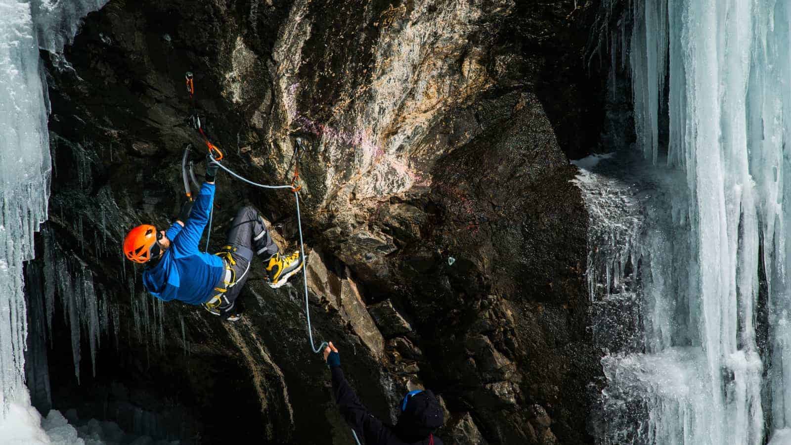 Un hombre está escalando una traicionera cascada helada.