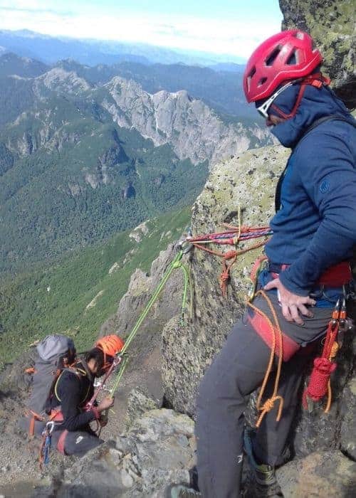 Un hombre escala una montaña con una cuerda.