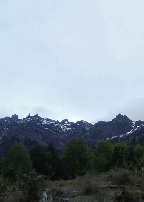 Una cadena montañosa con montañas coronadas de peinetas al fondo.