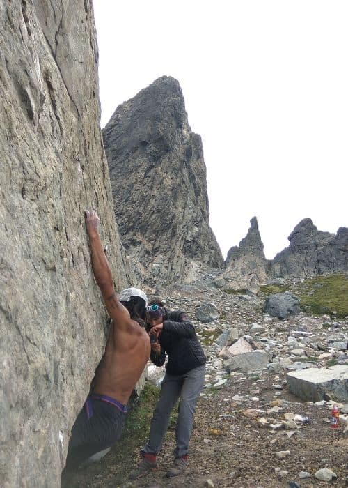 Un hombre trepa a una roca en la montaña, equipado con sus fieles peinetas.