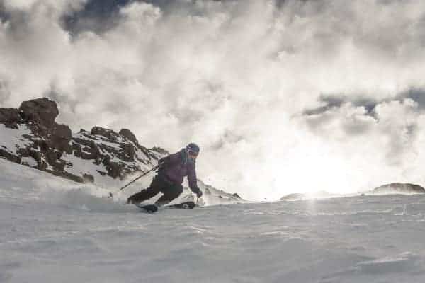 Una persona entusiasmada esquiando por una montaña cubierta de nieve.