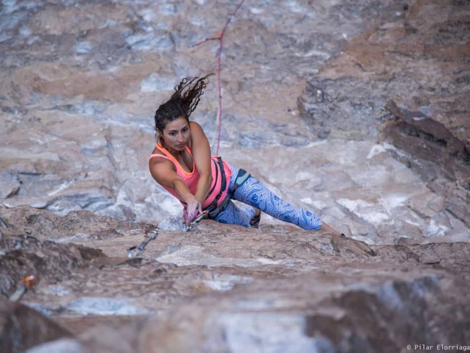 Una mujer está escalando rocas mientras usa un arnés.