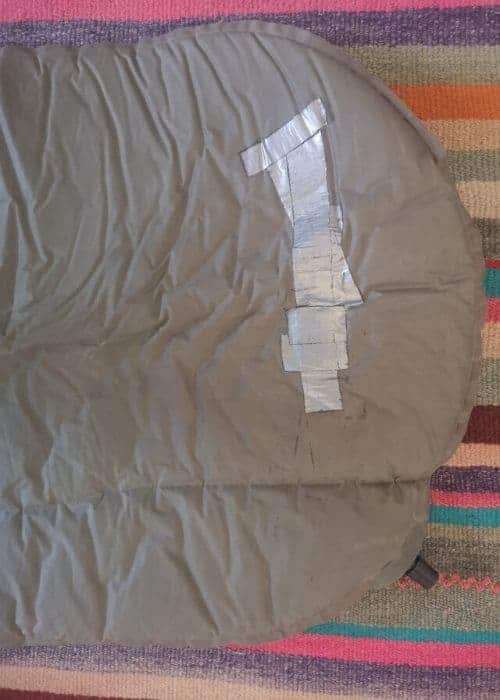 Descripción: Un saco de dormir en una alfombra con cinta adhesiva en ella.