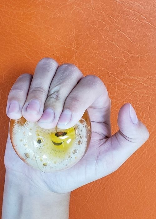 La mano de una persona sosteniendo una bola naranja.