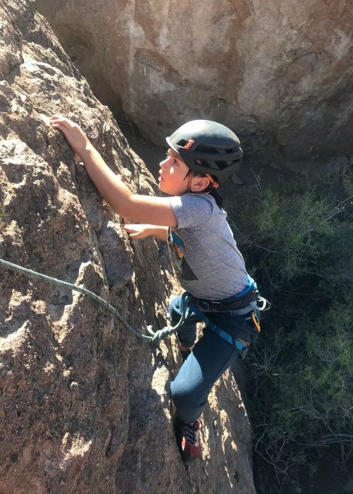 Un joven disfrutando de una aventurera escalada al aire libre sobre una roca en el desierto.