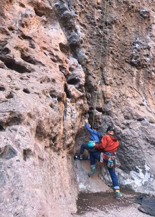 Un padre y un hijo se embarcan en un viaje de aventuras al aire libre, escalando juntos una roca en un cañón.
