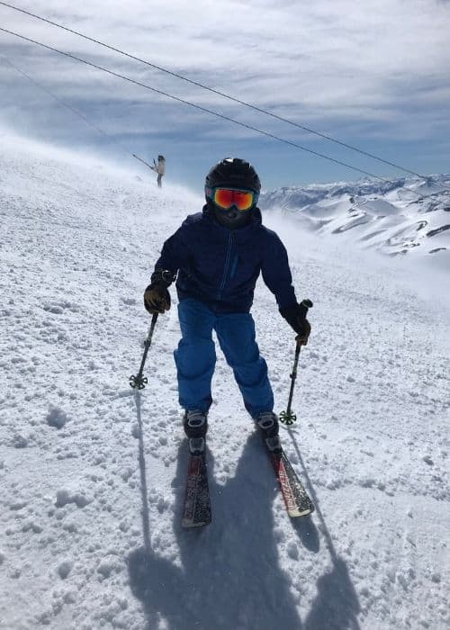 Un niño disfruta de la diversión al aire libre esquiando y se aventura fuera de su zona de confort en una pendiente cubierta de nieve.