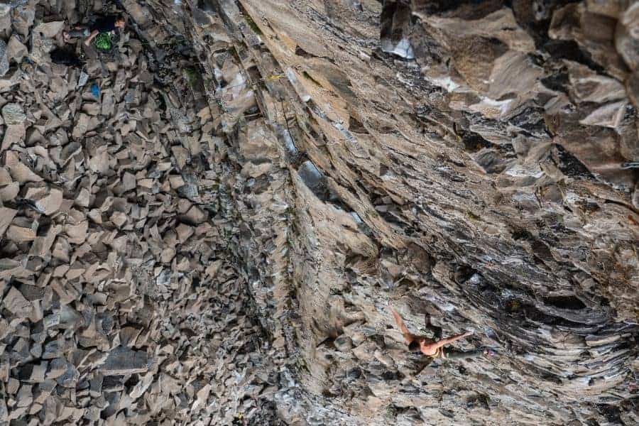 Un escalador está practicando escalada deportiva en un acantilado rocoso.