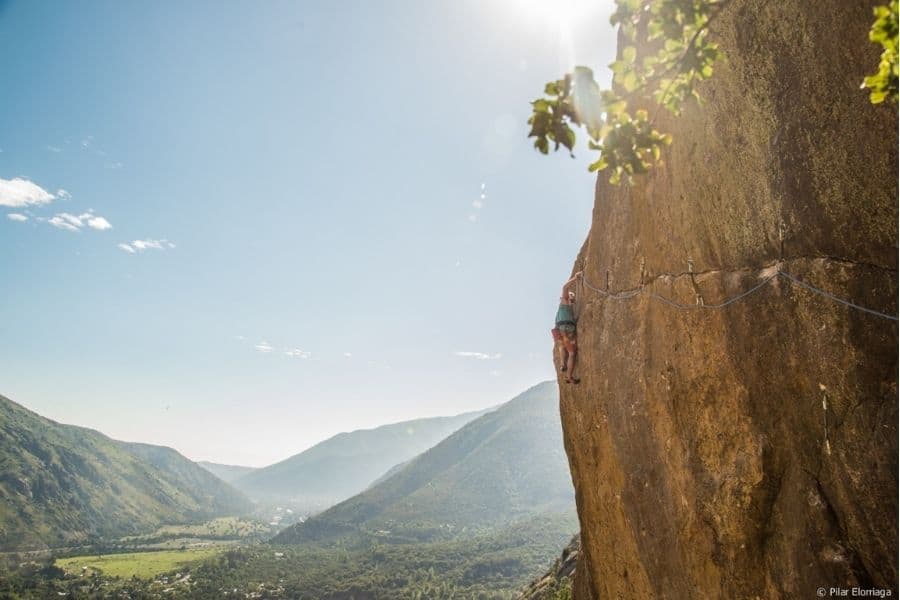 Un escalador deportivo está escalando un acantilado en las montañas.
