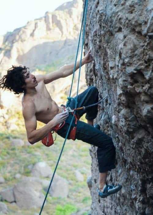Un joven practicaba escalada deportiva sobre una roca en el desierto.