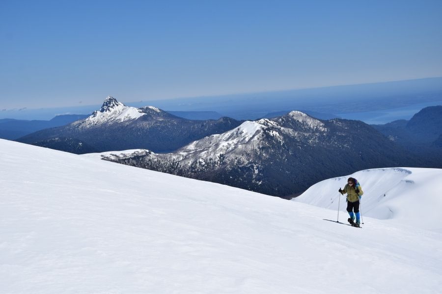 Una persona esquiando por una montaña antillanca con montañas al fondo.