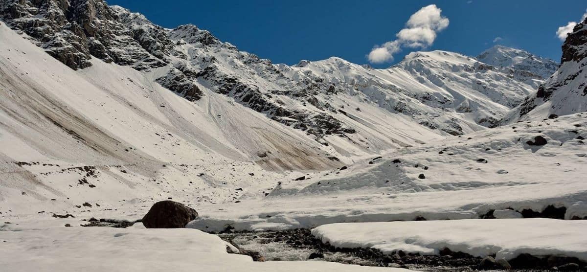 Una montaña cubierta de avalanchas y un arroyo que la atraviesa.