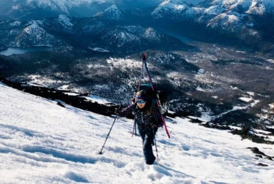 Una persona caminando por el Volcán Lanín cubierto de nieve, experimentando la belleza invernal de la montaña.