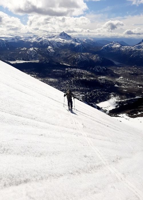 Un hombre desciende esquiando por una montaña cubierta de nieve cerca del majestuoso Volcán Lanín.