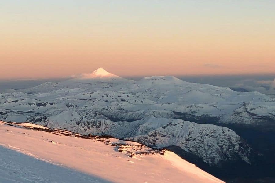 Una montaña cubierta de nieve, específicamente el majestuoso volcán Lanín, se ve desde la cima de otra montaña cubierta de nieve durante la temporada invernal.