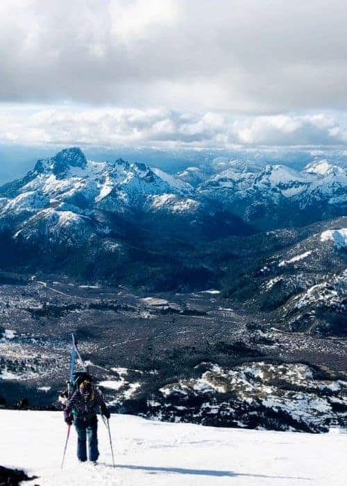 Un esquiador parado en la cima del nevado volcán Lanín, disfrutando del paisaje invernal.