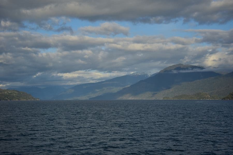 Un pintoresco escenario de un gran cuerpo de agua con montañas de fondo, incluyendo la majestuosa presencia del Volcán Yates de los Andes.