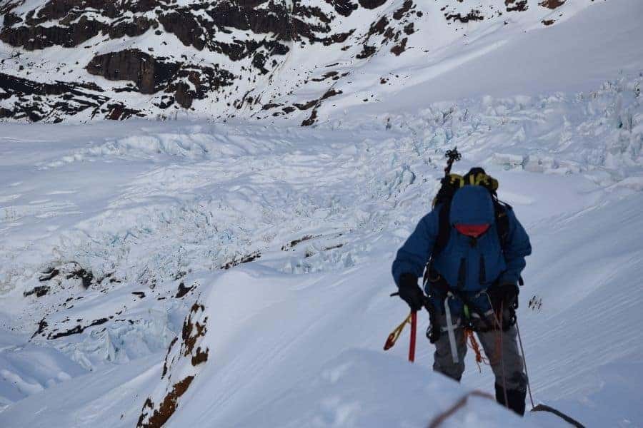 Un hombre está subiendo una montaña cubierta de nieve en los Andes.