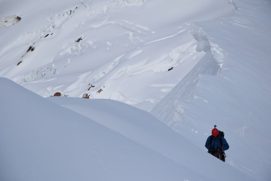 Una persona subiendo la ladera de una montaña cubierta de nieve llamada Volcán Yates.