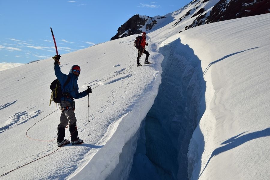 Dos personas paradas en la ladera de una montaña nevada en los Andes.