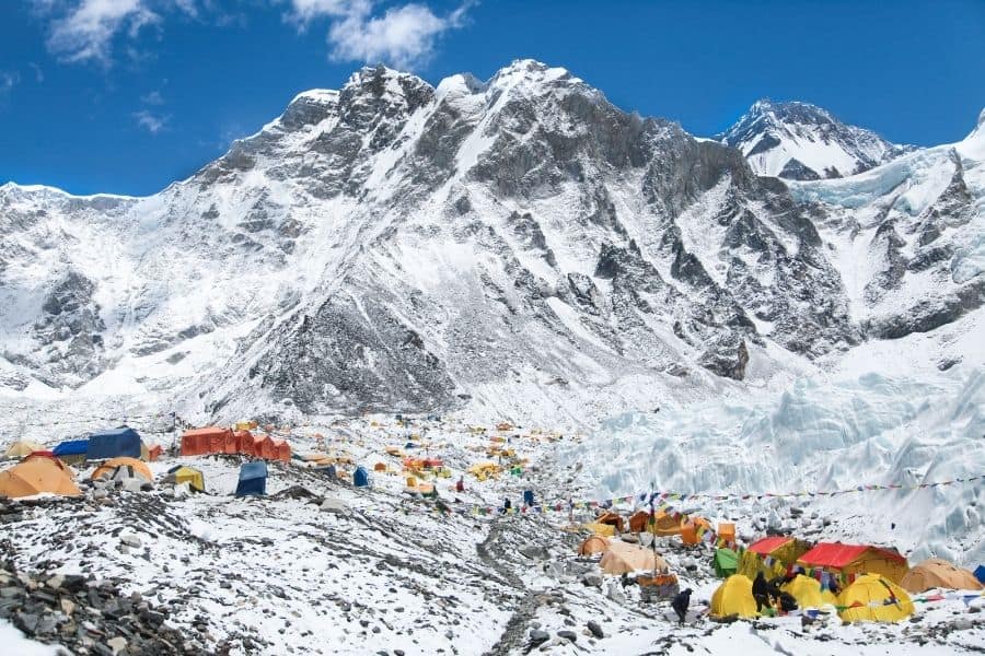 Un grupo minimalista de tiendas de campaña ubicadas en la cima de una montaña nevada, que ofrecen un escape al aire libre sin tecnología.