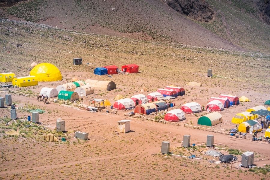 Una experiencia minimalista de acampar al aire libre en el desierto cerca de una montaña, combinando tecnología con naturaleza.