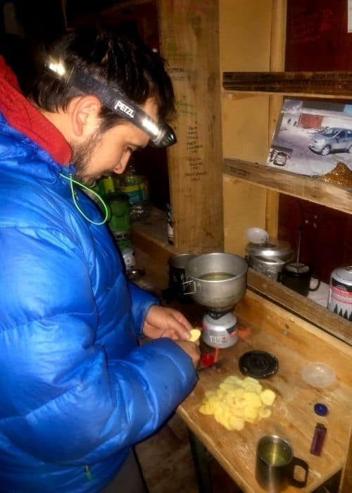 Un hombre con una chaqueta azul preparando comida en la cocina.