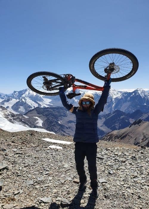 Un hombre sostiene una bicicleta en la cima de una montaña.