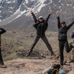 Descripción: Un grupo de personas disfrutando de una experiencia al aire libre en la cima de una montaña, con montañas en el fondo. Al aire libre