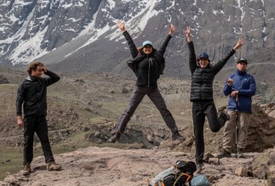 Descripción: Un grupo de personas disfrutando de una experiencia al aire libre en la cima de una montaña, con montañas en el fondo. Al aire libre