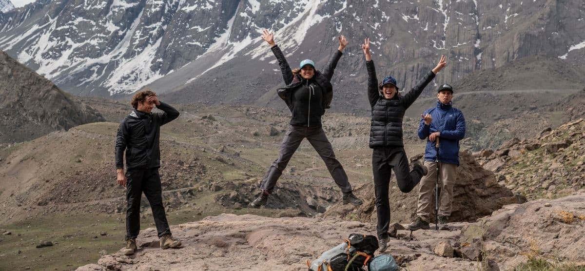 Descripción: Un grupo de personas disfrutando de una experiencia al aire libre en la cima de una montaña, con montañas en el fondo. Al aire libre