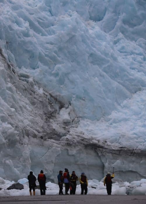 Un grupo de personas de pie frente a un gran glaciar en la Patagonia.