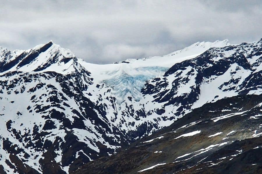 Un explorador contempla la montaña cubierta de nieve en O'Higgins, con un glaciar resplandeciente al fondo.