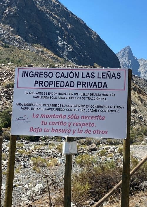 Un cartel frente a una montaña con el Cajón Las Leñas al fondo.