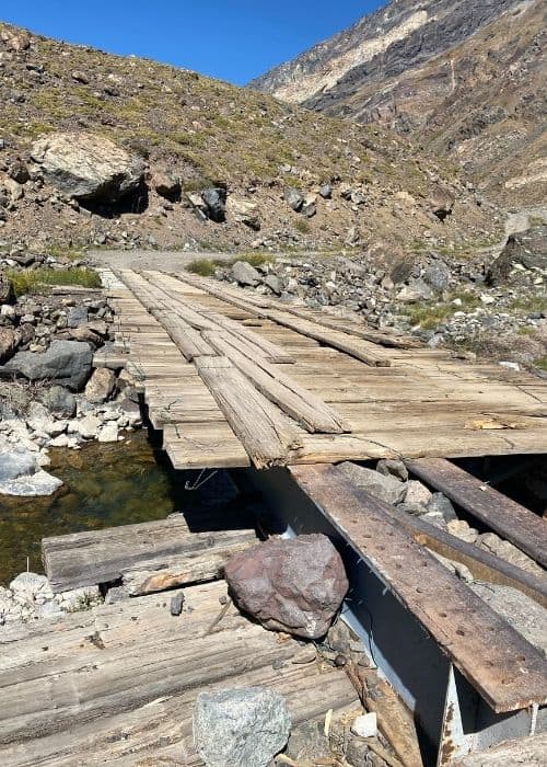 Un puente de madera terrestre que salva un arroyo en las montañas del Cajón Las Leñas.
