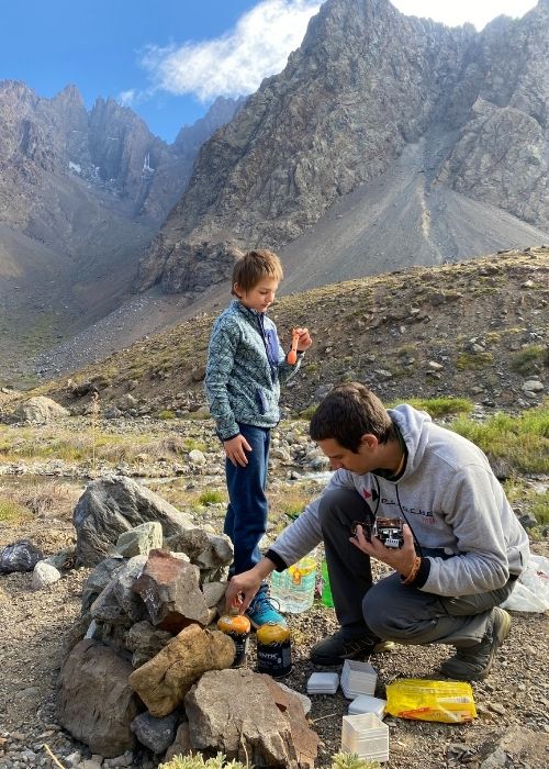 Un hombre y un niño preparando comida en las montañas del Cajón Las Leñas.