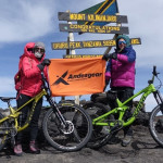 Dos mujeres poderosas posando con sus bicicletas en la cima de una montaña en África.