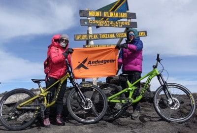 Dos mujeres poderosas posando con sus bicicletas en la cima de una montaña en África.